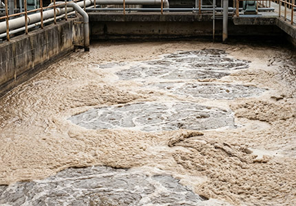 褐色・灰色の粘り気のある泡が発生した様子の曝気槽